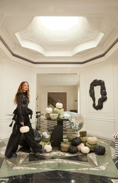 a woman standing in the middle of a room surrounded by pumpkins and other decorations