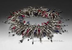 a silver bracelet with red, white and blue beads is shown on a gray surface