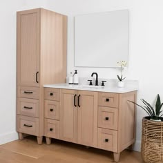 a bathroom vanity with two sinks and a mirror on the wall above it next to a plant