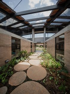 the walkway is lined with stepping stones leading to an open air space that has glass doors and windows