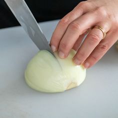 a person is cutting up an onion on a white counter top with a large knife