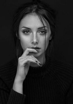 a black and white photo of a woman with her hand on her chin looking at the camera