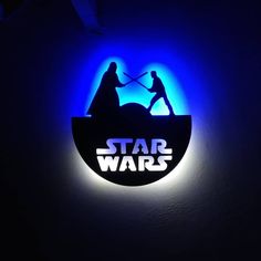 the star wars logo is lit up in blue and white light with two people holding swords