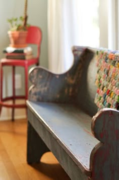 an old wooden bench sitting on top of a hard wood floor next to a red chair