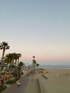 the beach is lined with palm trees and people walking on the sand near the water