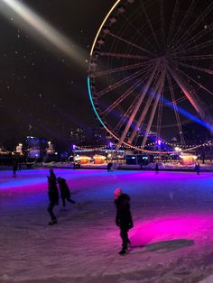 people skating on an ice rink at night with lights in the sky and ferris wheel behind them