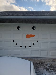 a garage door decorated like a snowman with black eyes and an orange carrot nose