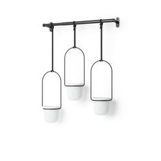 three lights hanging from a metal bar on a white wall with black bars and round glass shades