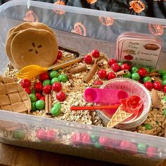 a plastic container filled with lots of food and candy on top of a wooden table