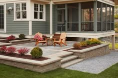 a patio with chairs and flowers in front of a house