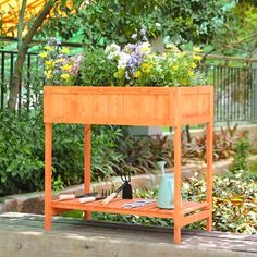 a wooden planter with flowers and gardening utensils sitting on top of it