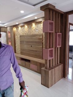 a man in a purple shirt is walking through a room with wooden furniture and lighting