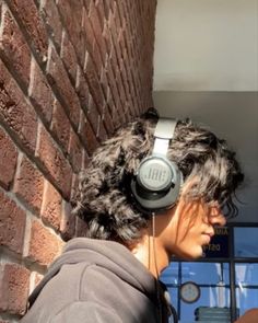 a woman wearing headphones standing next to a brick wall