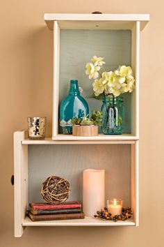 two shelves with candles, vases and flowers on them