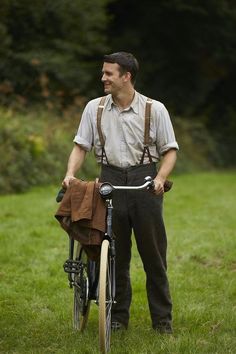 a man standing next to his bike in the grass