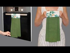 a woman holding up a green towel in front of an oven