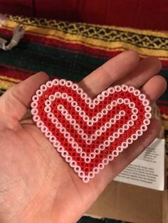 a hand holding a beaded heart in it's palm