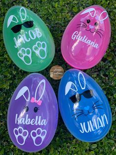 four personalized plastic easter eggs with bunny ears and paws on them sitting in the grass