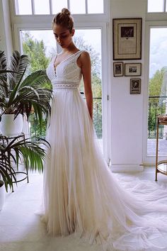 a woman in a white dress standing by a window