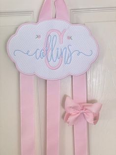 a pink door hanger with the letter j on it and a bow at the bottom