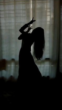 the silhouette of a woman standing in front of a window