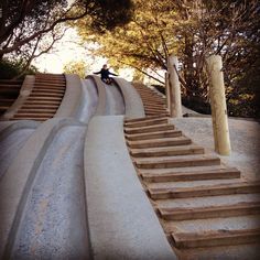 a person riding a skateboard down the side of a set of stairs in front of trees