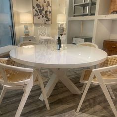 a white table with four chairs and a wine bottle on the table in front of it