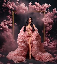 a woman in a pink dress is sitting on a chair surrounded by clouds and flowers