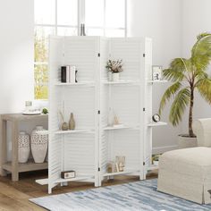 a living room with white furniture and a palm tree