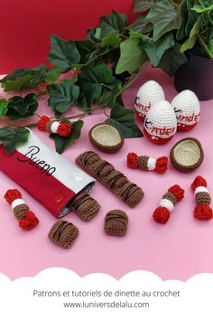 some crocheted items are sitting on a pink surface next to a potted plant