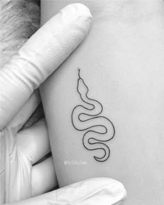 a black and white photo of a woman's arm with a snake tattoo on it