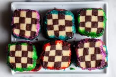 four squares of colorful cake sitting on top of a white plate next to each other