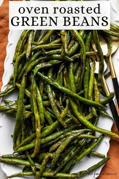 cooked green beans on a white plate with chopsticks next to it and the title overlay reads oven roasted green beans