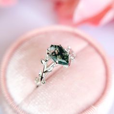 a close up of a ring on a pink velvet case with flowers in the background