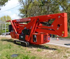 a large red crane sitting on the side of a road