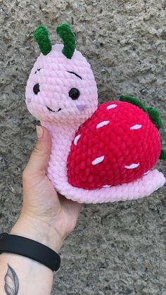 a hand holding a small knitted toy with a strawberry on it's side