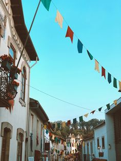 there are many colorful flags hanging from the buildings