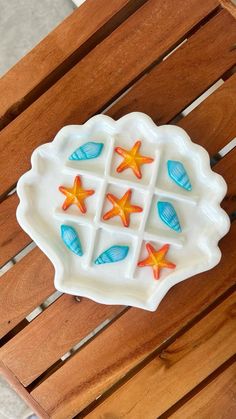 a white plate with starfishs and shells on it sitting on a wooden table