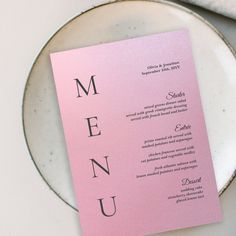 a pink menu card sitting on top of a white plate