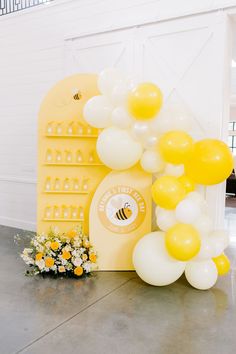 a bunch of balloons that are sitting on the ground next to a sign and some flowers