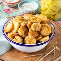 a bowl filled with fried food on top of a wooden cutting board