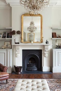 a living room filled with furniture and a chandelier hanging from the ceiling over a fire place