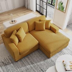 a large yellow couch sitting on top of a living room floor next to a white coffee table