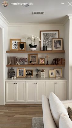 a living room filled with lots of furniture and framed pictures on the wall above it