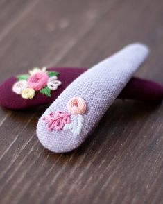 two purple slippers with flowers on them sitting on a wooden table next to each other