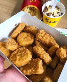 a box filled with fried food next to a cup of ice cream