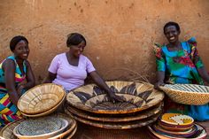 three women sitting next to each other with baskets on the ground in front of them