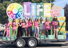 a group of young women standing on the back of a truck in front of a sign