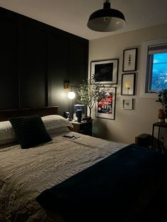 a bedroom with a bed and pictures on the wall next to it's windows