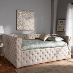 a white day bed sitting on top of a hard wood floor next to a window